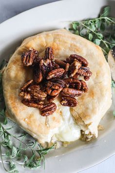 a pecan filled pastry on a white plate with green sprigs around it