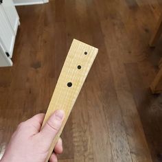 a person holding a wooden stick with holes in it's middle on a wood floor