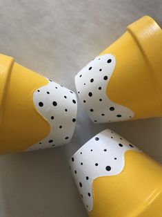 four yellow and white cups with black dots on them are sitting in a circle together