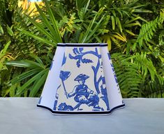 a blue and white lamp shade sitting on top of a table next to green plants