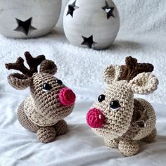 two crocheted reindeers sitting on a bed next to each other with their noses open