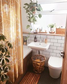 a bathroom with a toilet, sink and bathtub next to a plant in the corner