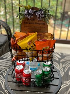 a basket filled with drinks and snacks on top of a metal table next to a fence