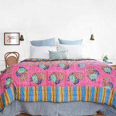 a bed with pink and blue bedspread on top of it