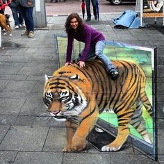 two women standing on top of a painting of a tiger in the middle of a sidewalk