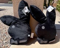 two black stuffed animals sitting next to each other on top of a stone slab in front of a building