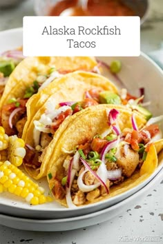 a white plate topped with three tacos and corn