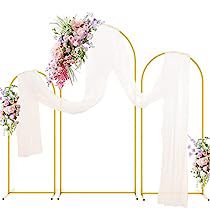 a wedding arch with flowers and veils on the top is set against a white backdrop