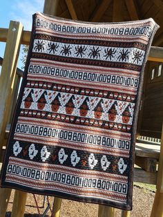 a quilt is hanging on a wooden chair in front of a building with a picnic table