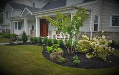 a house with landscaping in front of it and flowers on the lawn next to it