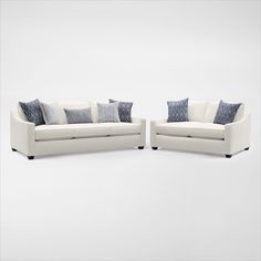 two white couches with blue and gray pillows on them, one is facing the other