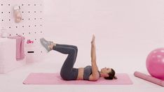 a woman doing an exercise on a pink mat in front of a gym ball and yoga mat