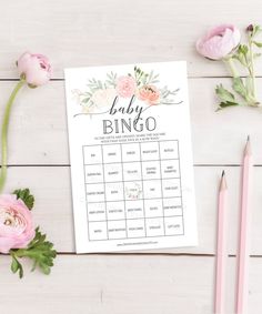 a floral bridal bingo game with pink flowers and pencils on the table next to it