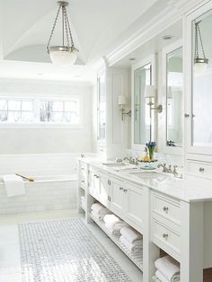 a large white bathroom with two sinks and mirrors