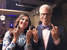 an older man and young woman posing for the camera with their fingers in the air