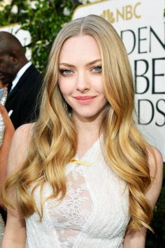 a woman with long blonde hair wearing a white dress and posing for the camera at an event