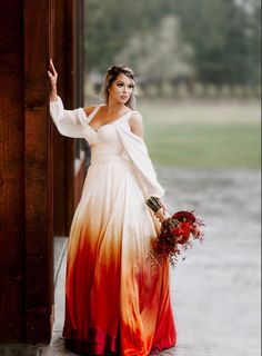 a woman in a long dress is standing by a door with her hand on the wall