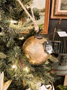 an ornament hanging from the top of a christmas tree in front of a birdcage