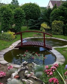 a wooden bridge over a small pond surrounded by flowers