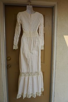 "Size 13 Gunne Sax prairie dress fits smaller - please see measurements. Zips in the back with adjustable tie at the back of the waist. Condition - has one small spot mid skirt to the side - see last photo. Measurements taken across front lying flat 18\" across front armpit to armpit 14\" across front of waist (ties tighter) 59\" length" Fitted Cream Victorian Dress With Long Sleeves, Fitted Cream Maxi Dress Floor-length, Cream Long Sleeve Maxi Dress For Wedding, Beige Long Sleeve Maxi Dress With Lace Trim, Fitted Floor-length Cream Vintage Dress, Cream Fitted Floor-length Vintage Dress, Cream Floor-length Fitted Vintage Dress, Fitted Floor-length Maxi Dress With Lace Trim, Fitted Off White Floor-length Maxi Dress