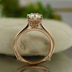 a close up of a diamond ring on a rock with water in the back ground