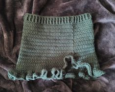 there is a crocheted skirt on top of a bed with brown and green sheets