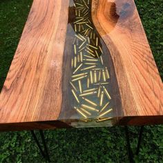 a table made out of wood and glass in the middle of grass with an arrow pattern on it