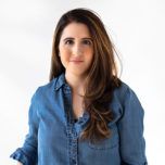 a woman standing in front of a white background with her hands on her hips and looking at the camera