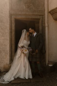 a bride and groom standing in front of a doorway