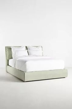 the bed is made up with white sheets and pillows, but no headboard or foot board