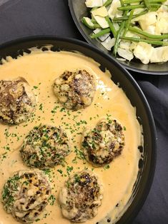 a pan filled with meatballs covered in gravy next to a bowl of vegetables