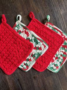 three crocheted christmas stockings on a wooden table with red and green trimmings