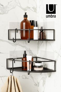 two black shelves with soap, lotion and other items on them against a marble wall