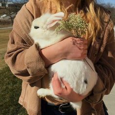 a woman holding a small white rabbit in her arms