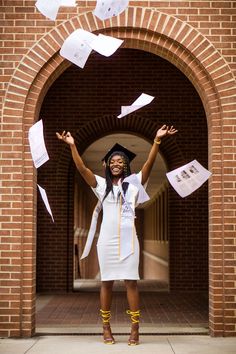 a woman in a graduation cap and gown throwing papers into the air with her hands