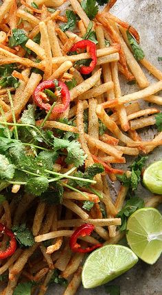 a pile of french fries with cilantro, lime and red peppers on top