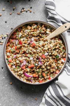 a bowl filled with lentils, onions and carrots next to a striped towel