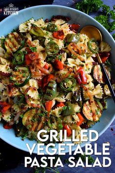 grilled vegetable pasta salad in a blue bowl with a serving spoon on the side