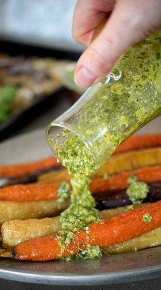 someone is dipping sauce on carrots with pesto