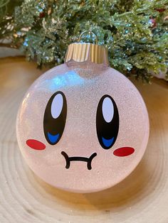 a glass ornament with a face drawn on it sitting next to a christmas tree