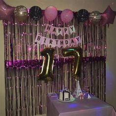 a birthday party with balloons and streamers on the wall, including a cake table