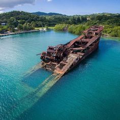 an old ship sitting in the middle of some water