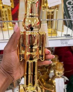 a person holding up a gold statue in front of some other golden items at a store