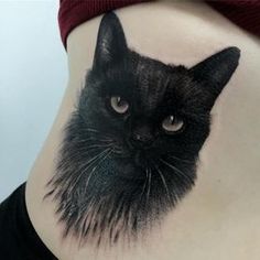 a black cat tattoo on the side of a woman's stomach, with her eyes wide open