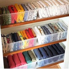 an organized closet filled with folded shirts and other items in plastic bins on shelves