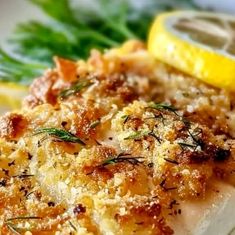 a close up of fish on a plate with lemon wedges and parmesan cheese