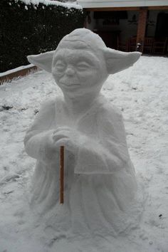 a snow man holding a broom in the middle of a yard covered in white snow