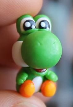 a small toy frog sitting on top of someone's finger