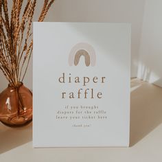 a card that says diaper raffle next to a vase with dried grass in it