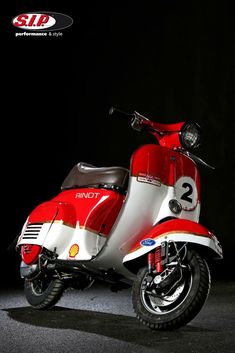 a red and white scooter parked in a dark room with the number 2 on it